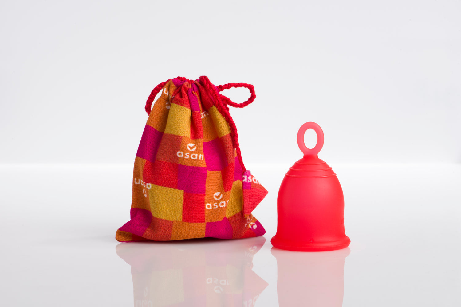 Red silicone menstrual cup with a patterned drawstring bag on a white background