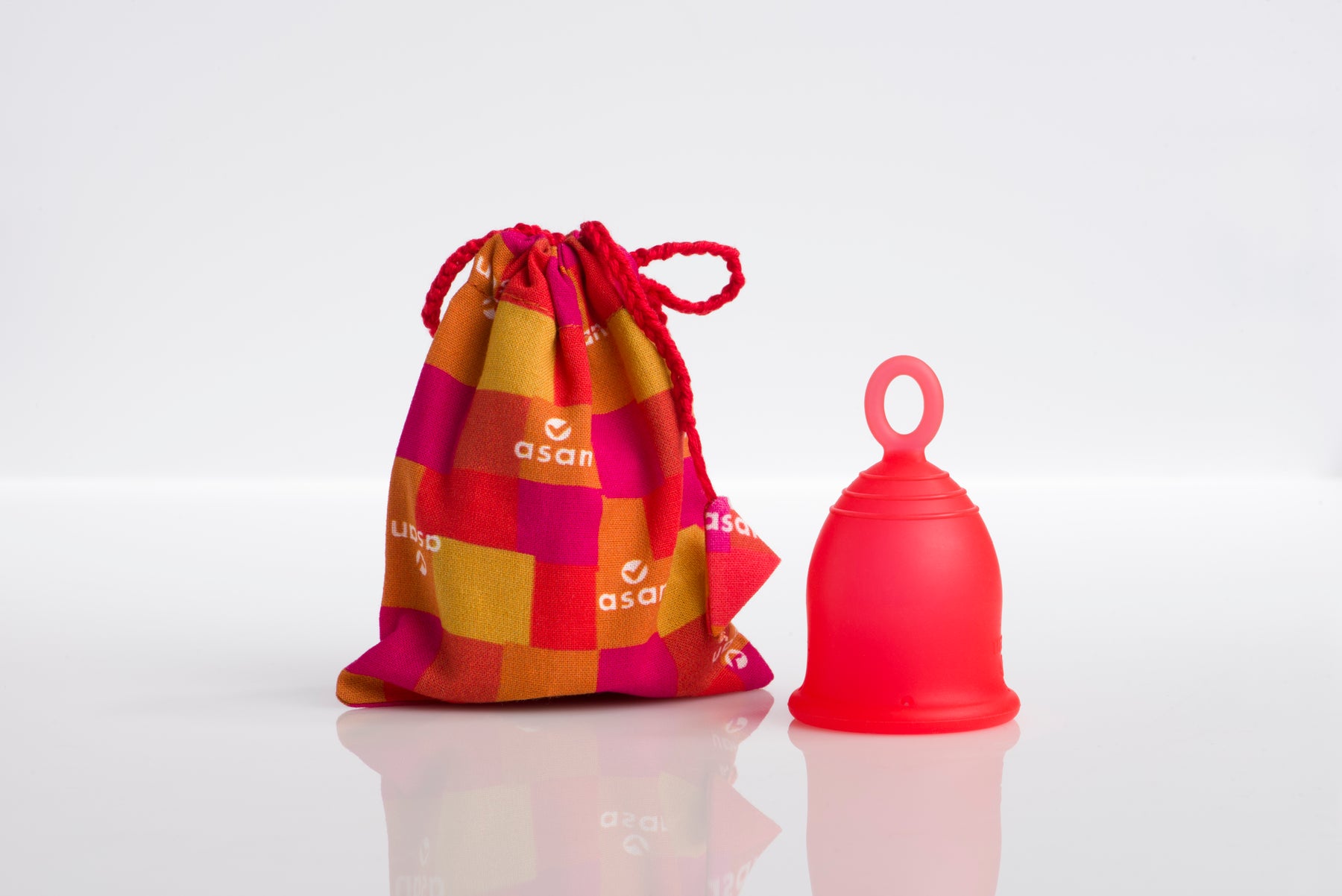 Red silicone menstrual cup with a patterned drawstring bag on a white background