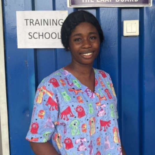 Person wearing a colorful scrub top with animal patterns in front of a blue door.